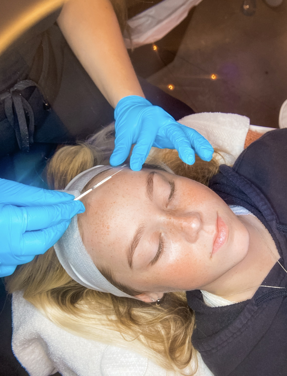 A Shine Auburn esthetician performing a dermaplane treatment on a relaxed client